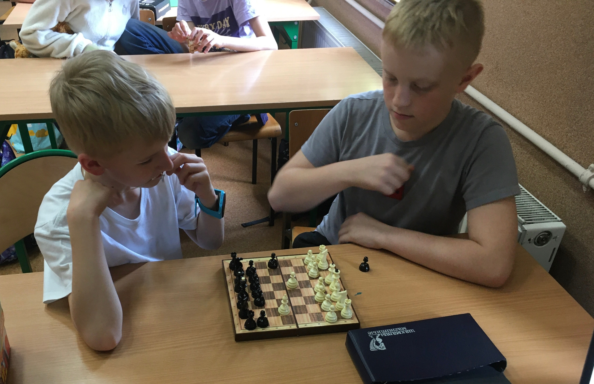 Dwóch uczniów gra w szachy w sali na lekcji matematyki.