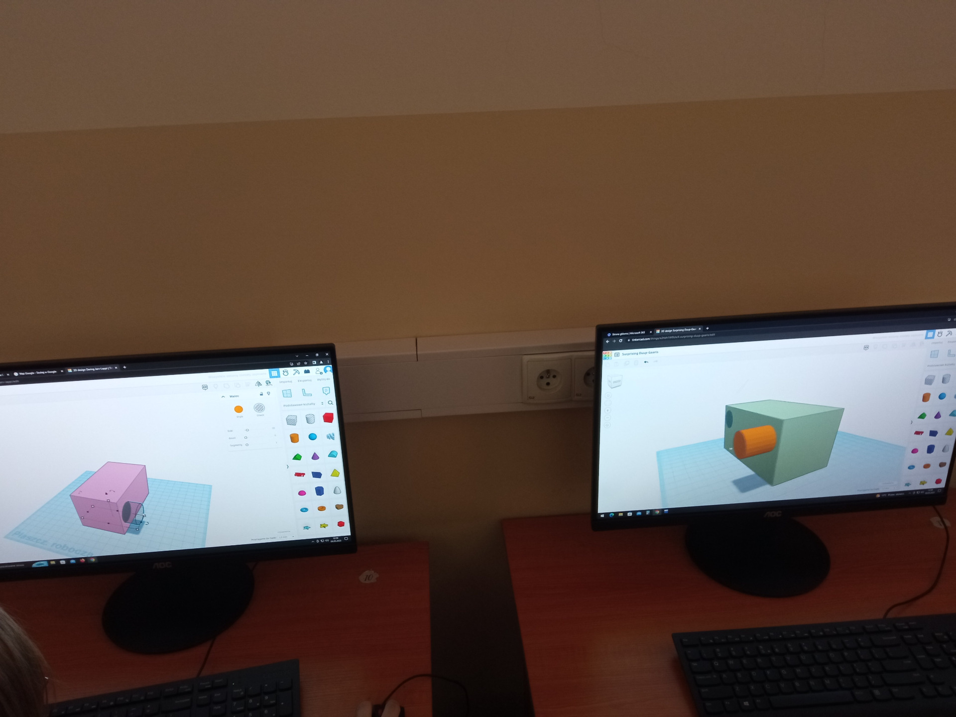 Widok dwóch monitorów, na których uczniowie projektują model 3D.