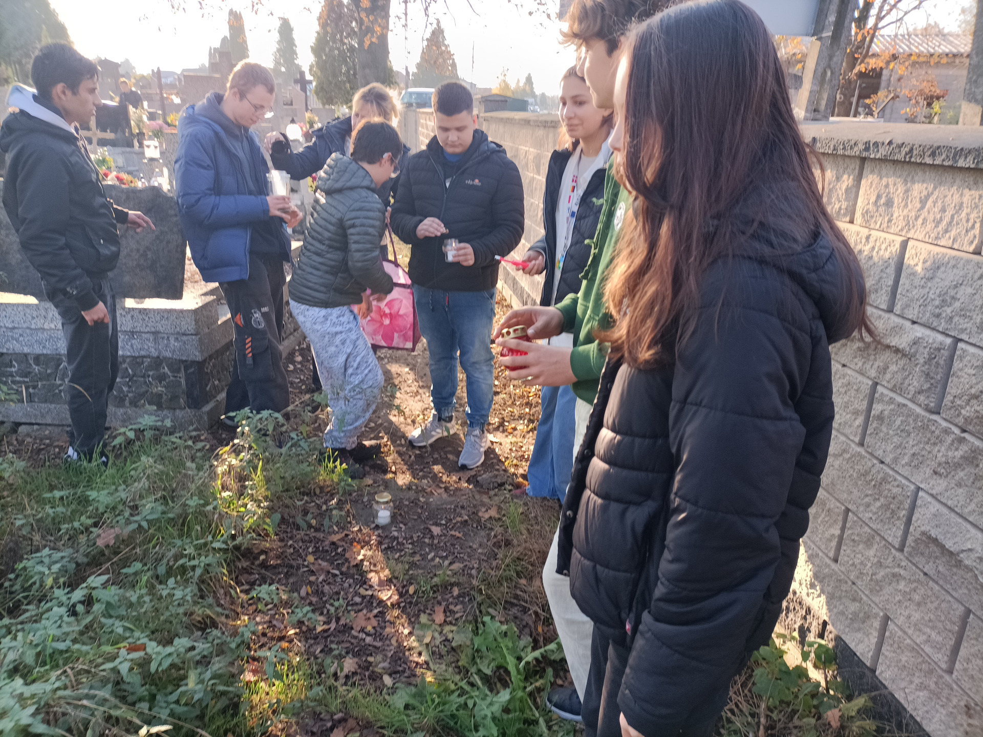 Wolontariusze z obu szkół przygotowują znicze do umieszczenia ich na grobach