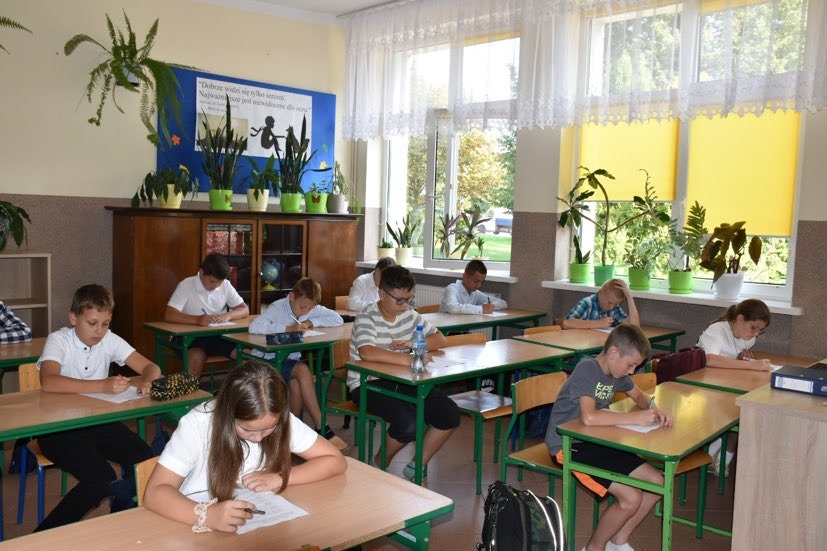 Uczniowie siedzą w ławkach i piszą test konkursowy