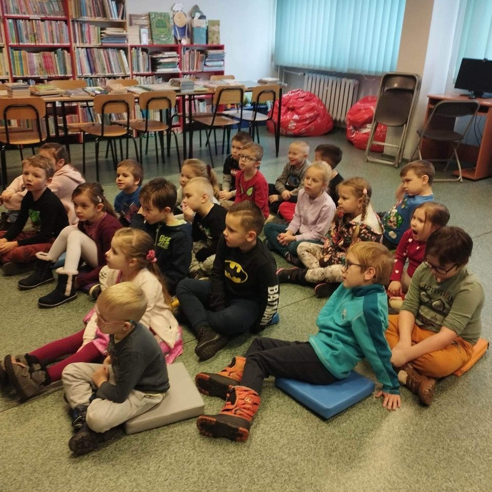 dzieci w bibliotece siedzą na dywanie