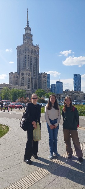 3 uczennice stoją na chodniku, za ich plecami widać Pałac Kultury.