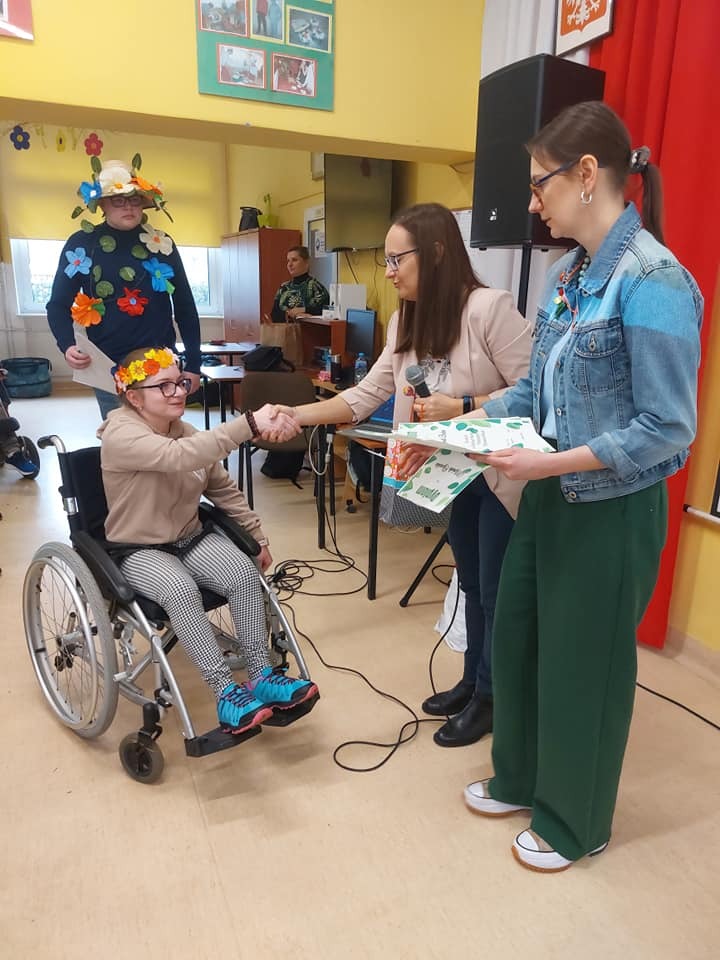 Uczenica na wózku inwalidzkim odbiera nagrodę - dyplom  od organizatora