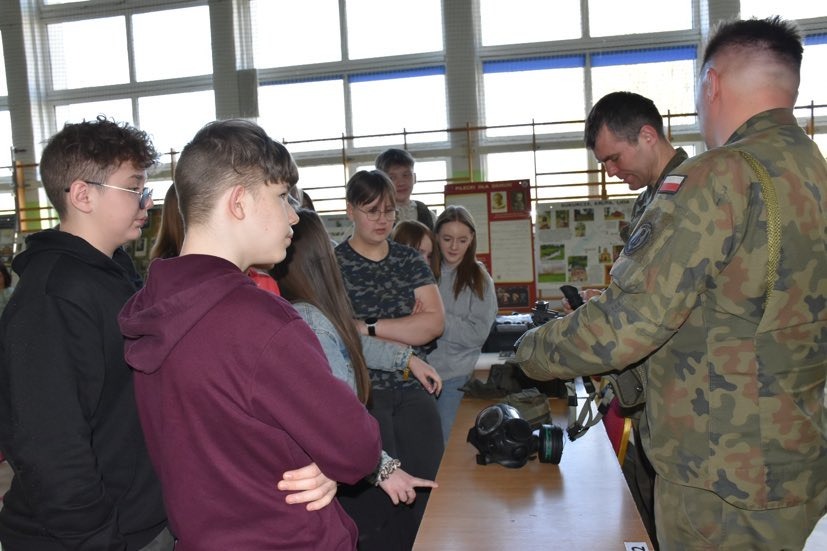 Żołnierze pokazują uczniom elementy wyposażenia wojskowego i wyjaśniają zasady jego wykorzystania