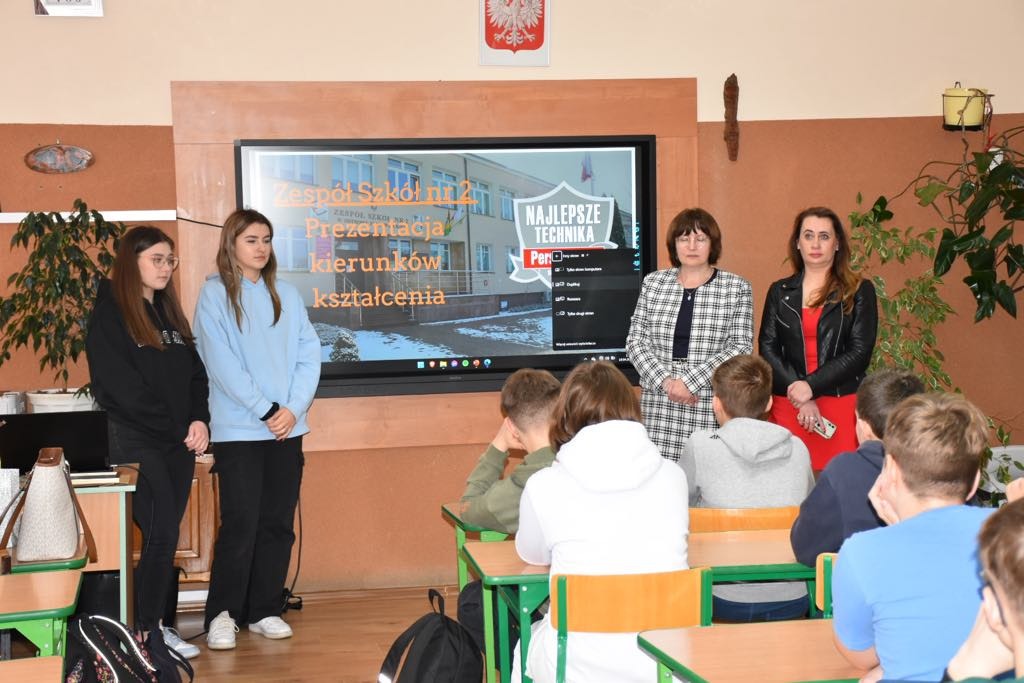 Uczniowie i nauczyciele "Ekonomika" przy monitorze interaktywnym prezentują ofertę edukacyjną szkoły.