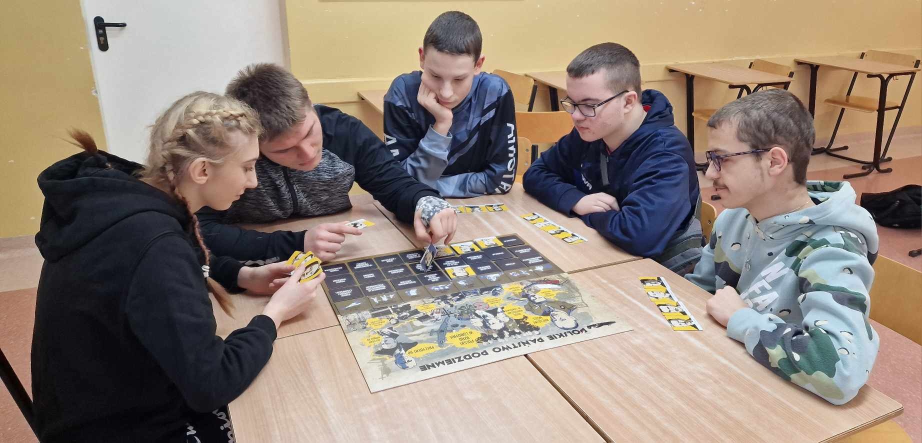 5 uczniów gra przy stoliku w historyczną grę planszową