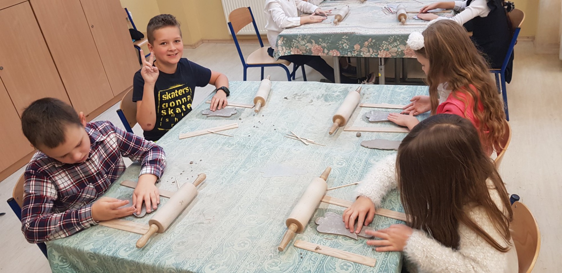 Dzieci pracują przy stolikach, wygładzanie szablonu anioła