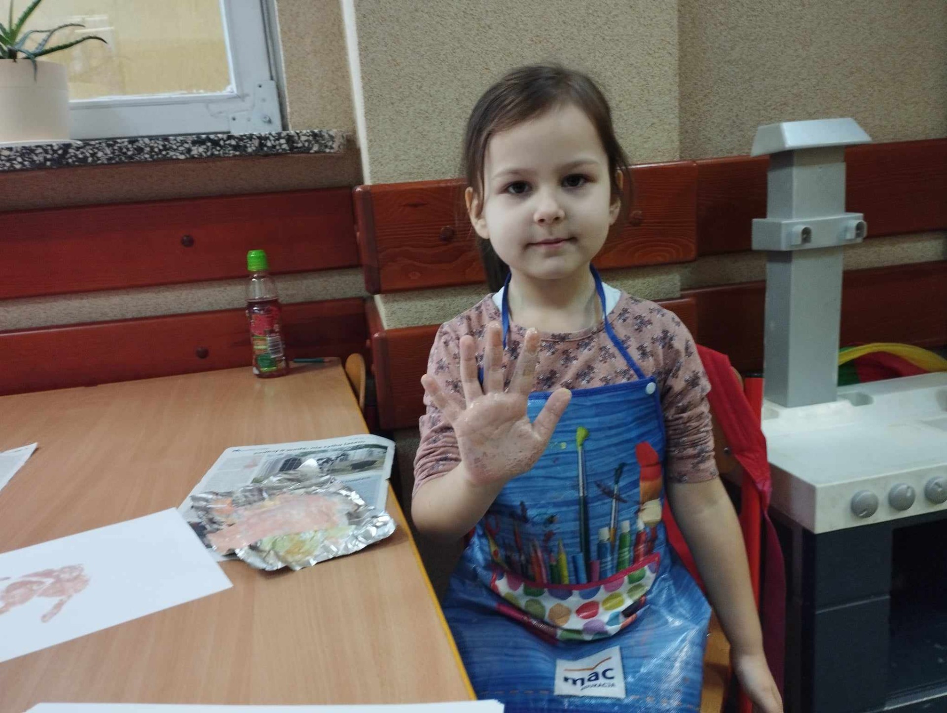 Przedszkolaki wykonują zadania z projektu "Kosmiczne dłonie" pomalowanymi kolorowo dłońmi.