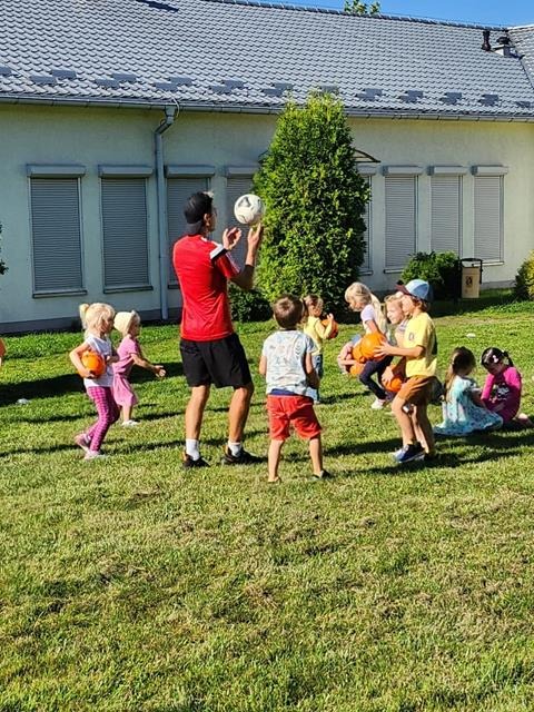 dzieci grają w piłkę na podwórku